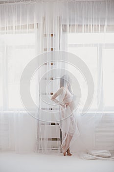 Beautiful pregnant woman with long hair standing near window