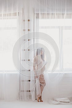 Beautiful pregnant woman with long hair standing near window
