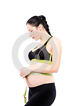 Beautiful pregnant woman measures the abdominal circumference centimeter tape photo