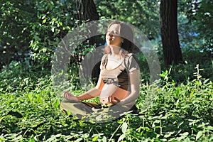 Beautiful pregnant woman meditate in park