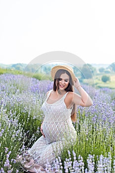 beautiful pregnant woman posing in white dress at violet