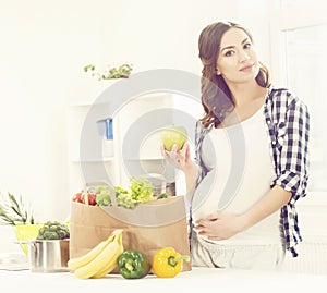 Beautiful pregnant woman with shopping bags in kitchen. Motherhood, pregnancy, maternity concept.