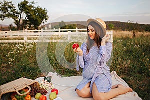 Beautiful pregnant woman show and eat red apple. Healthy food. Fresh fruits. Happy woman smile
