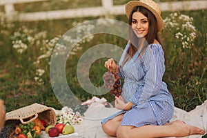 Beautiful pregnant woman show and eat red grapes. Healthy food. Fresh fruits. Happy woman smile