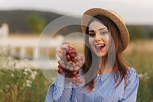 Beautiful pregnant woman show and eat red grapes. Healthy food. Fresh fruits. Happy woman smile