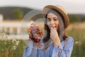 Beautiful pregnant woman show and eat red grapes. Healthy food. Fresh fruits. Happy woman smile