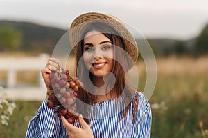 Beautiful pregnant woman show and eat red grapes. Healthy food. Fresh fruits. Happy woman smile