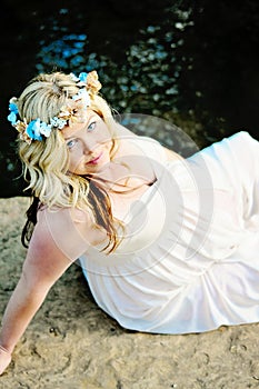 Beautiful pregnant woman sitting next to creek.