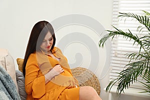 Beautiful pregnant woman sitting on sofa