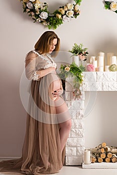 Beautiful pregnant woman standing by the fireplace