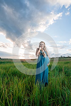 Beautiful pregnant woman standing on green grass