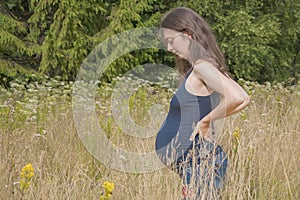 Beautiful pregnant woman standing in tall grass. Expectation of a child. Concept calm, pacification, relaxation