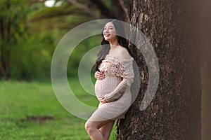 Beautiful pregnant woman stroking her belly in the park