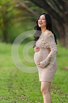 Beautiful pregnant woman stroking her belly in the park