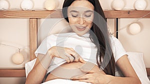 Beautiful pregnant woman stroking her belly and talking to her baby