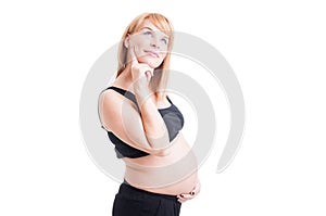 Beautiful pregnant woman thinking wondering or day-dreaming with