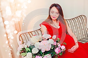 Beautiful pregnant woman touching her belly with hands in the living room having, the light give a cozy atmosphere.