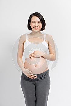Beautiful pregnant woman touching her belly with hands on a white background
