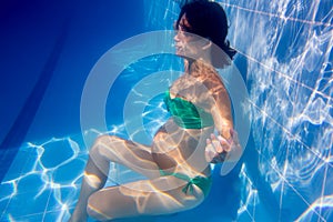 Beautiful pregnant woman underwater blue pool