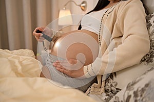 Beautiful pregnant woman using flashlight on belly to stimulate a baby's development, fertility infertility treatment, IVF,