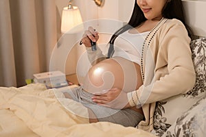 Beautiful pregnant woman using flashlight on belly to stimulate a baby's development, fertility infertility treatment, IVF,