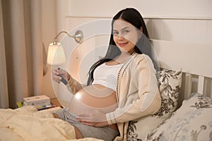 Beautiful pregnant woman using flashlight on belly to stimulate a baby's development, fertility infertility treatment, IVF,