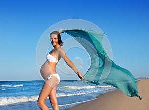 Beautiful pregnant woman walking on blue beach