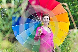 Beautiful pregnant woman walking under colorful umbrella