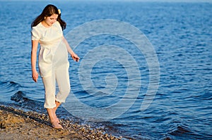 Beautiful pregnant woman walks along the shore