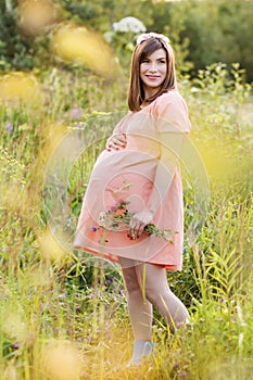 Beautiful pregnant woman walks in the park