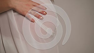 Beautiful pregnant woman with white silk on white background.