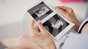 Beautiful pregnant woman wife holding ultrasound baby picture in her hand. Pregnancy woman and maternity healthcare