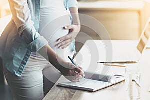 Beautiful Pregnant Woman Writing in Notebook.