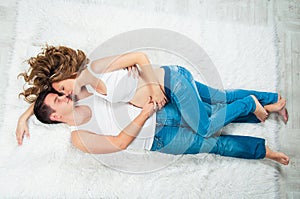 Beautiful pregnant young couple laying on top.