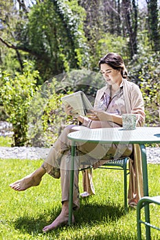 Beautiful pregnant young woman reading newspaper outdoors