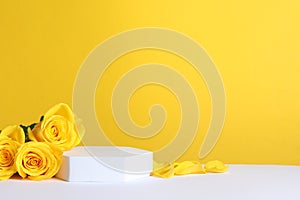 Beautiful presentation for product. Podium and roses on white table against yellow background, space for text