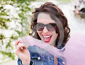 Beautiful pretty girl in sunglasses eating cotton candy at park