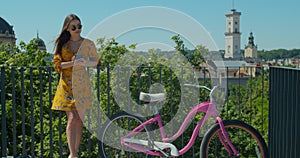 Beautiful pretty teenager girl riding a bicycle and using her mobile phone smartphone to communicate with friends