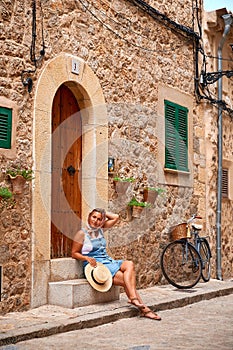 Beautiful pretty woman walking at old town pavement street with flowers and looking away. Travel concept