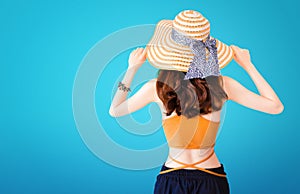 Beautiful pretty woman wearing a straw hat and sexy suit on blue background with Summer concept