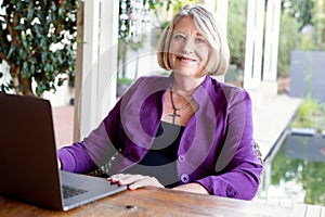 A beautiful professional senior woman working on her laptop from home