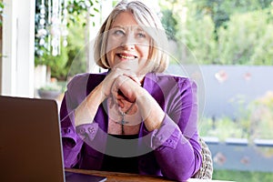 A beautiful professional senior woman working on her laptop from home