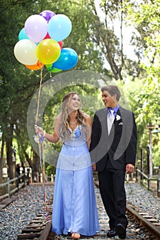 Beautiful Prom Couple Walking with Balloons Outside