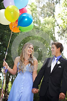 Beautiful Prom Couple Walking with Balloons Outside