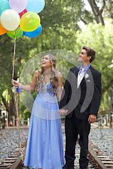 Beautiful Prom Couple Walking with Balloons Outside