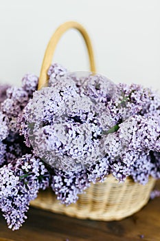 Beautiful purple lilac flowers bunch in a basket on wooden table