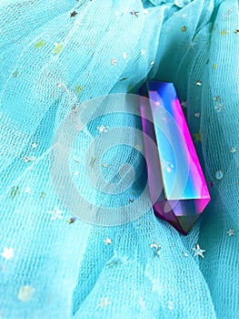 Beautiful purple pink crystal quartz aura lies on the blue fabric.