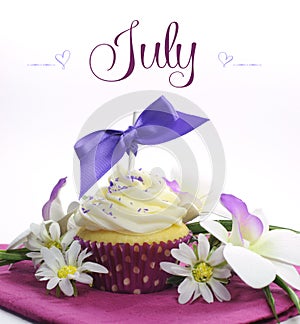 Beautiful purple and pink Summer theme cupcake with seasonal flowers and decorations for the month of July