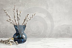 Beautiful pussy willow branches on white marble table, space for text