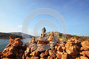 Beautiful Pyramid shape of stones arranged with Buddha statue in zen on rock mountain in seascape of sunset and sea horizon with